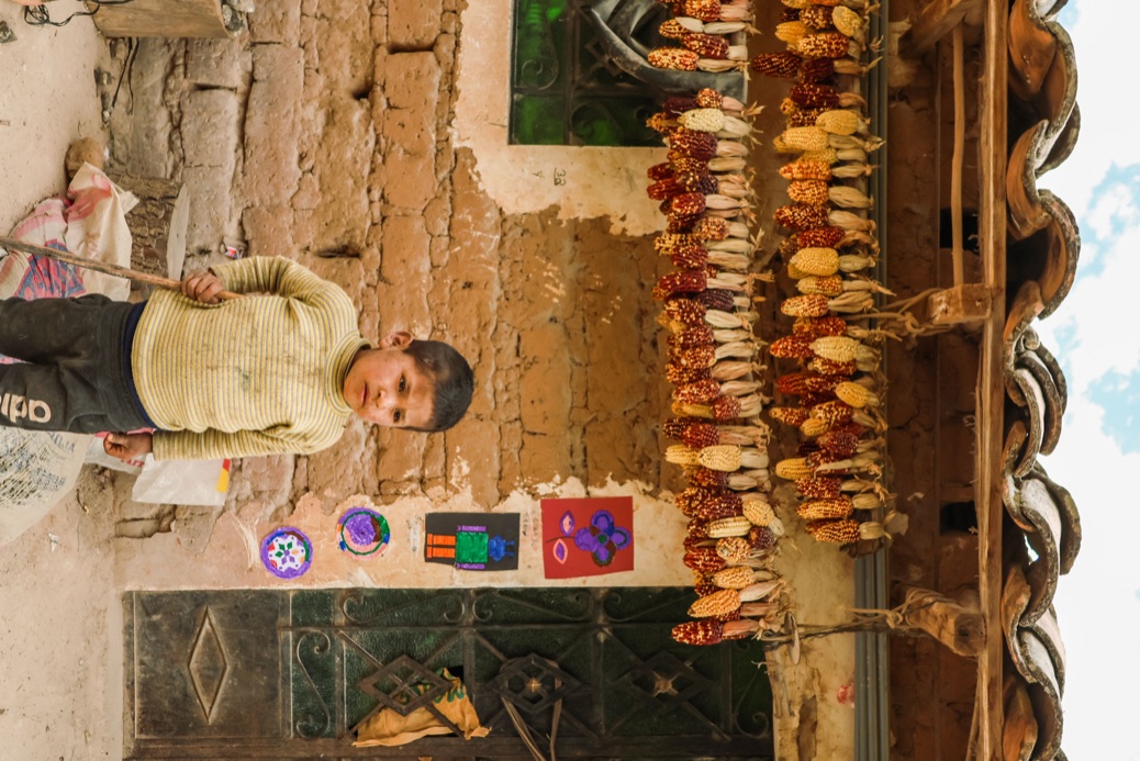 Boy standing beneath hanging corn