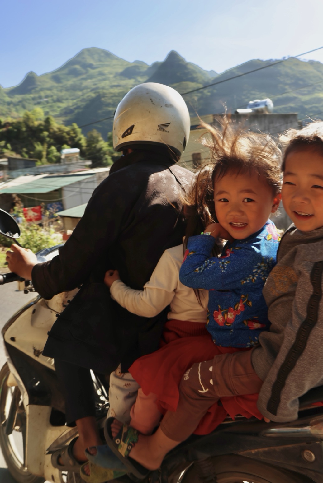 Family riding a motorbike through a mountain village