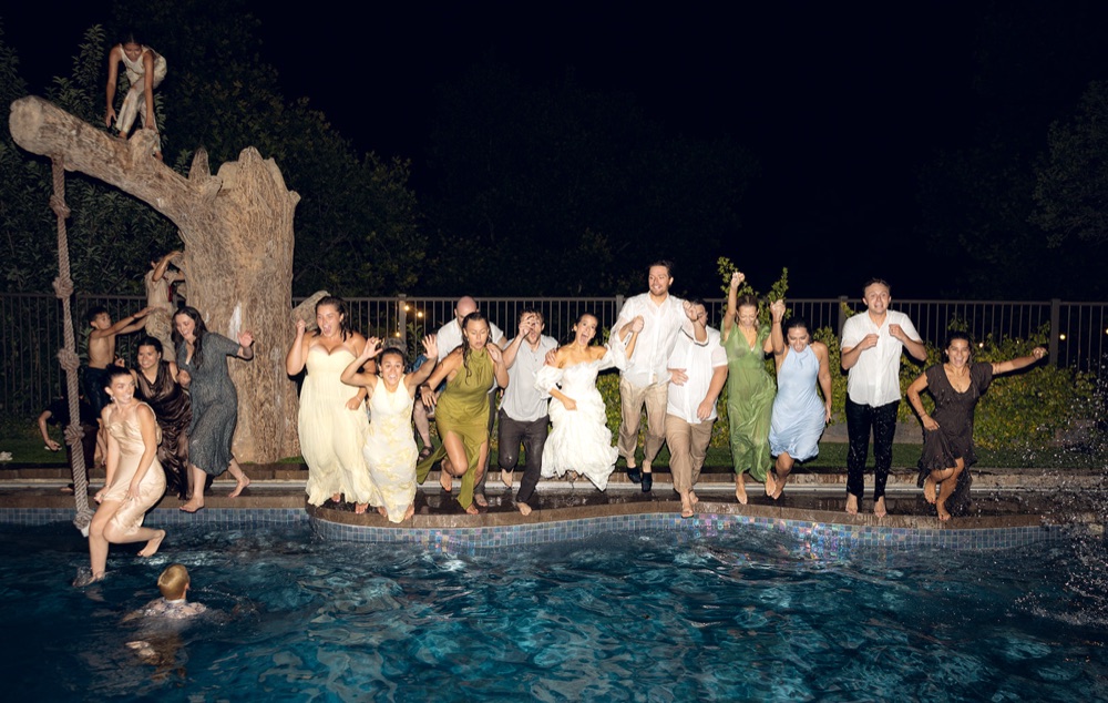 The whole wedding party jumping into the pool at night