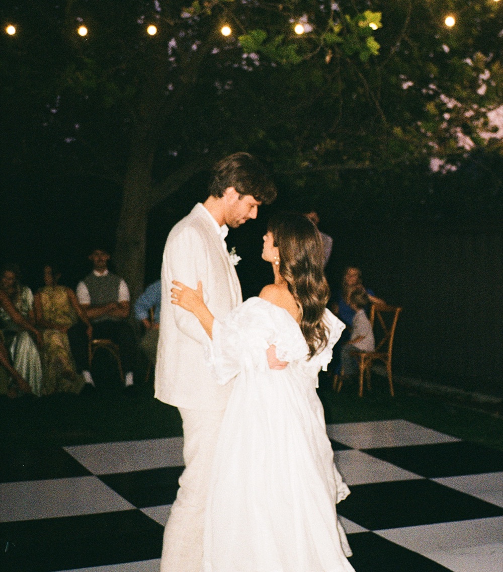 First dance on a checkerboard floor under string lights