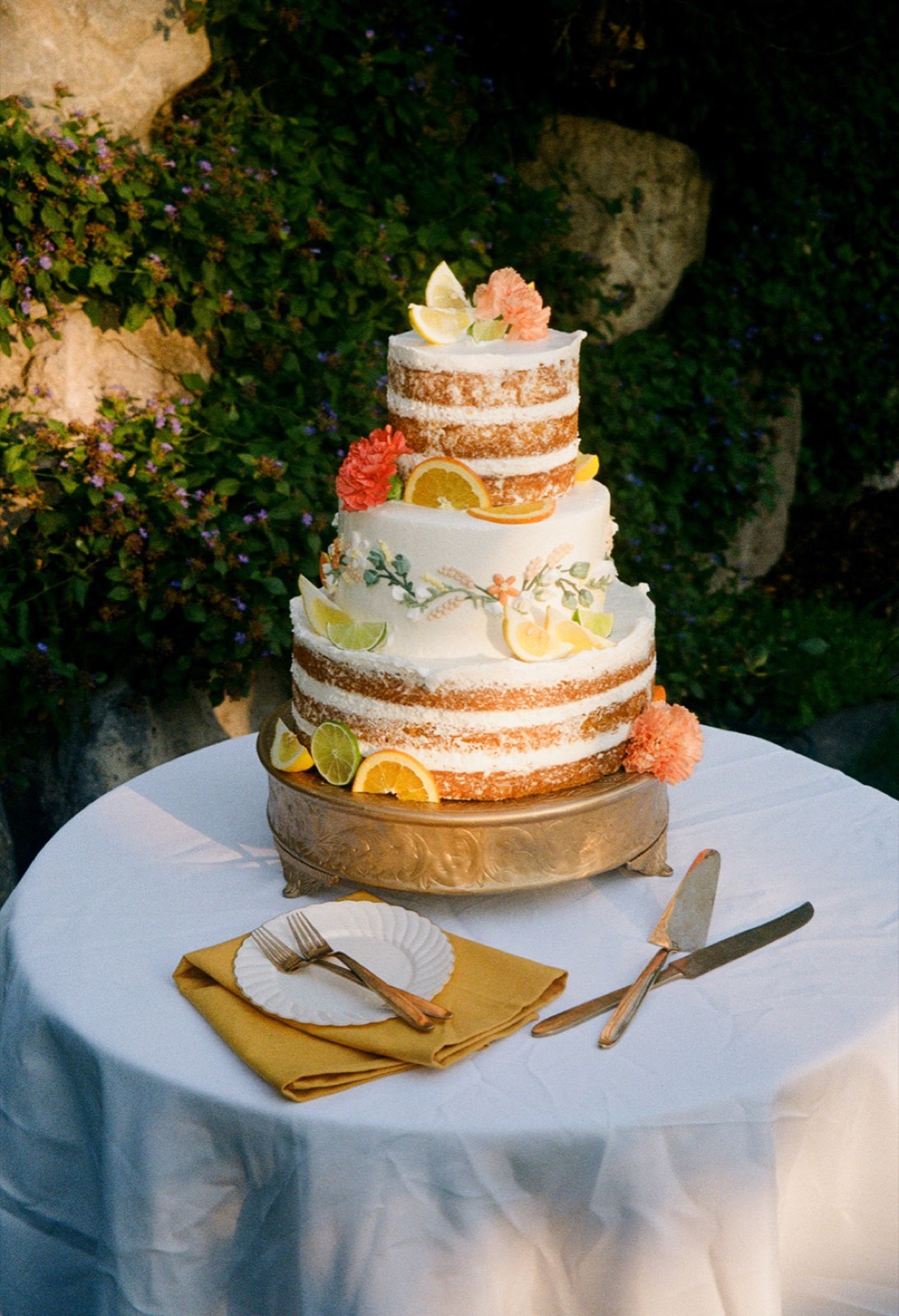 Three tier citrus wedding cake on a brass stand