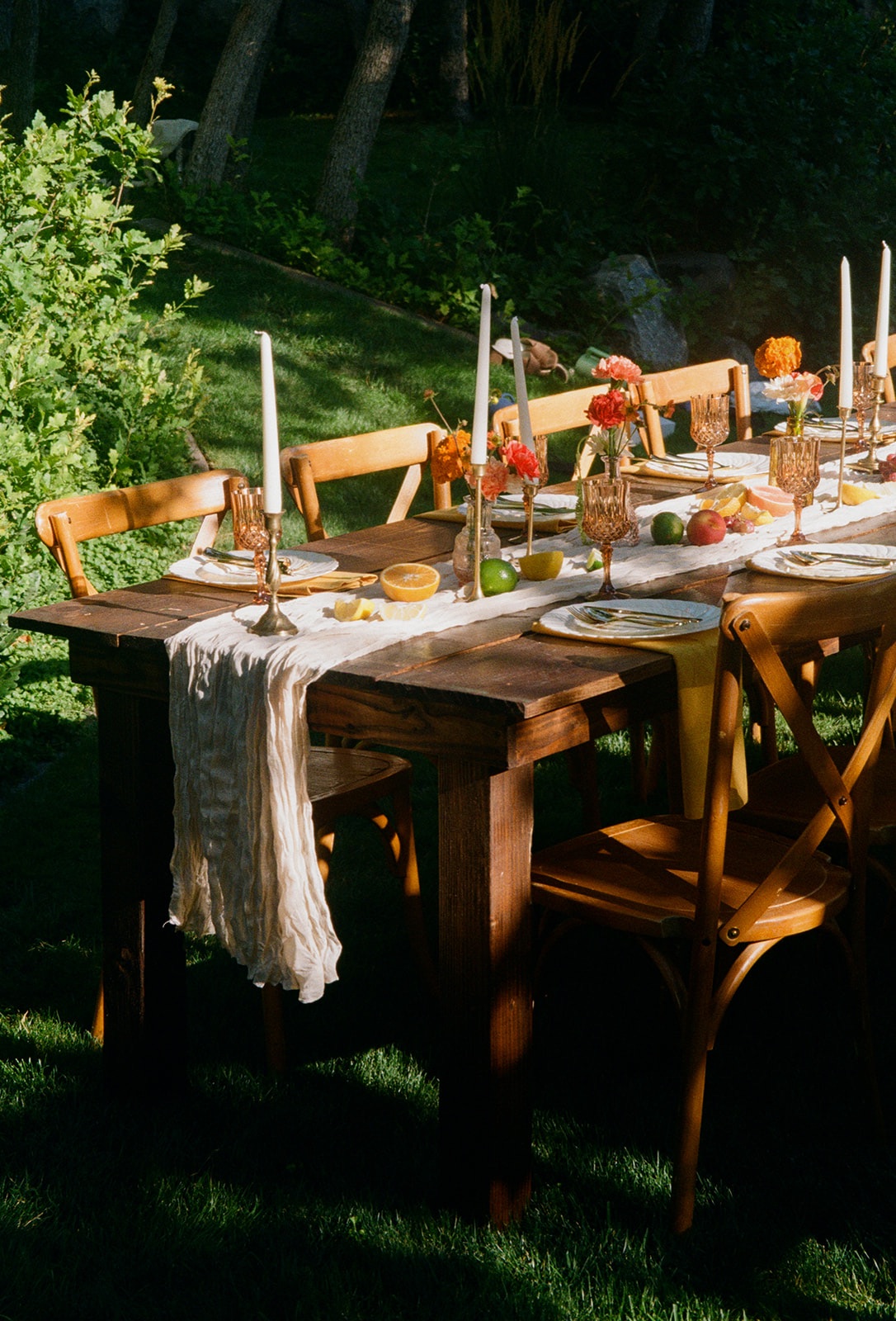 Backyard table set with citrus, tapers and a linen runner in evening light